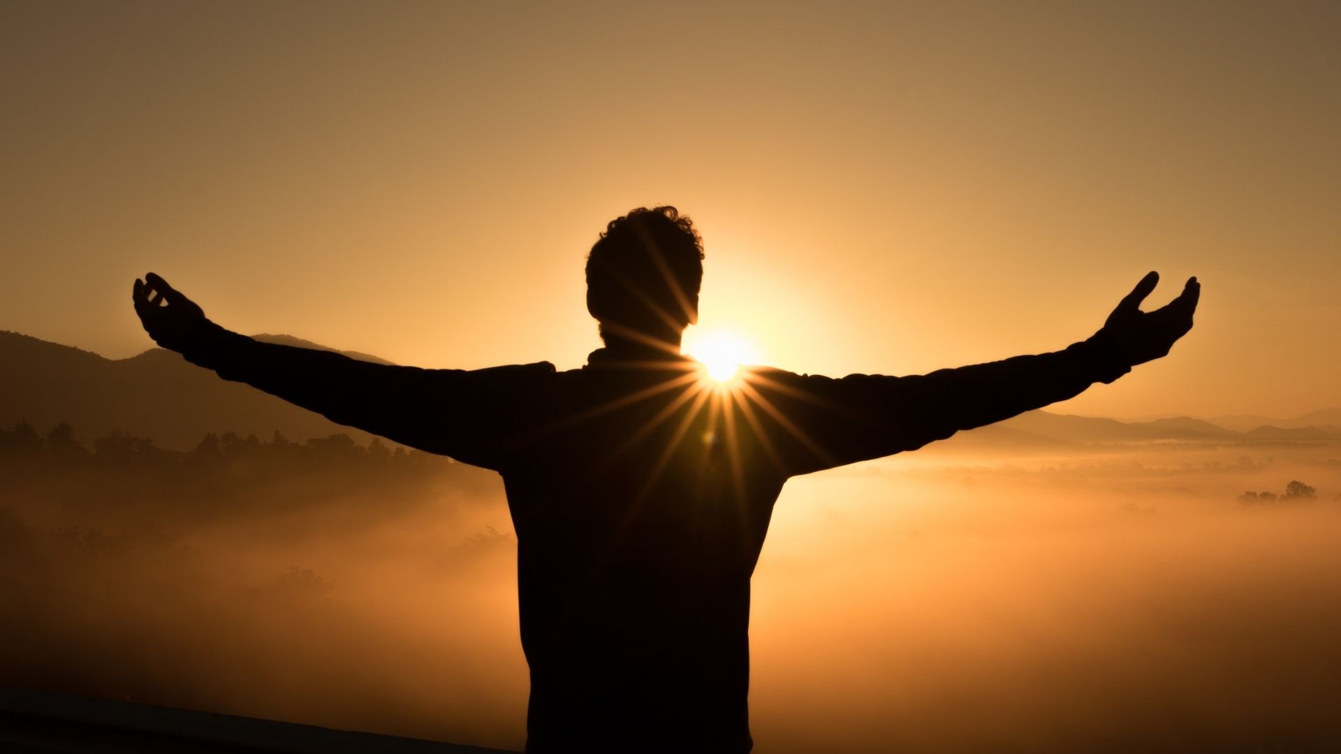 Man raising his hands as the sun sets